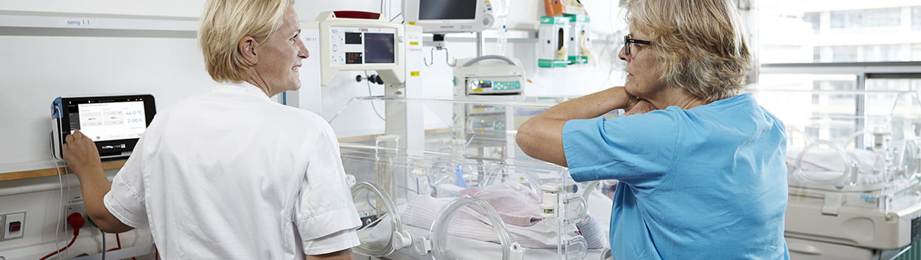 Situation hospitalière – deux soignants de l’unité de soins intensifs néonatals, utilisant un moniteur transcutané de Radiometer